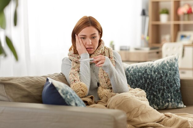 femme malade mesurant la température avec un thermomètre