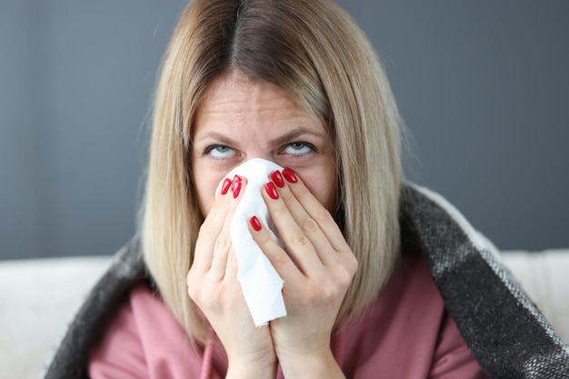 Une femme malade se mouche dans le concept de maladie saisonnière de mouchoir