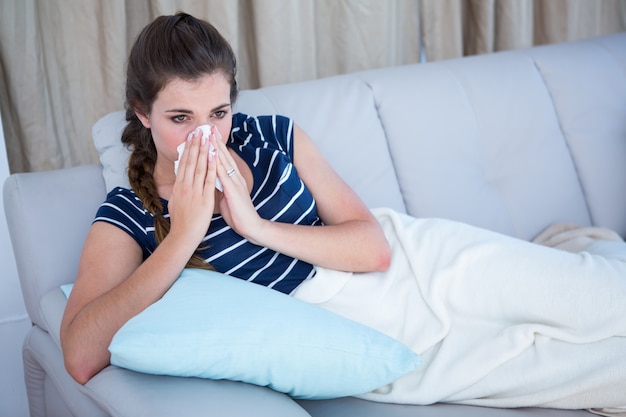 Femme malade se moucher sur le canapé