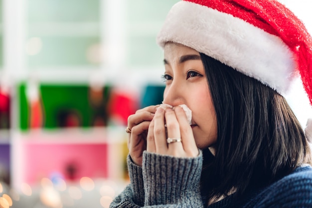 Femme malade se moucher le nez avec un mouchoir en papier et éternuer tout en ayant froid