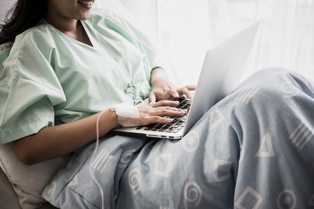 Femme malade travaille avec un ordinateur portable à l&#39;hôpital.