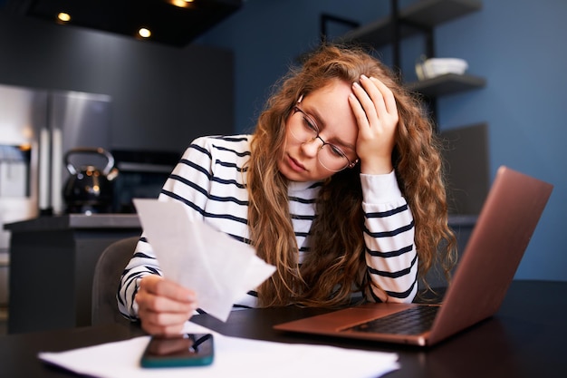 Une femme malheureuse calcule les dépenses sur les factures contrariées par l'augmentation des prix des services publics Femme comptant les chèques de paie dettes prêts reçus pour payer les impôts Inflation crise financière faible capacité de paiement