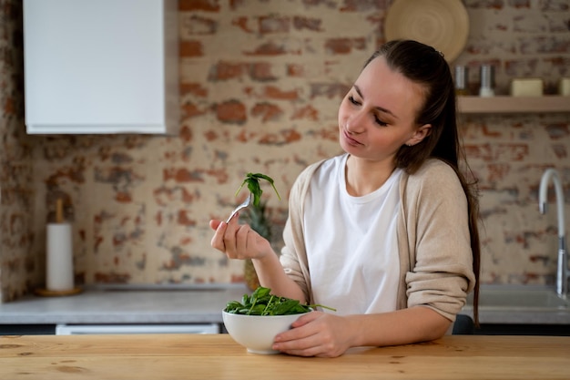 Une femme malheureuse mange de la salade verte pour un concept alimentaire sain et elle ne l'aime pas