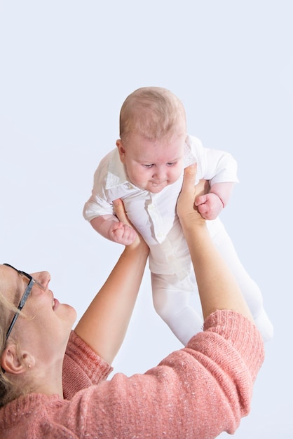 Femme maman joue avec son bébé vomit au-dessus de sa tête l'enfant rit drôle isolé