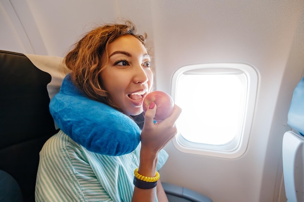 Photo une femme mange une collation aux fruits sains dans la cabine d'un avion, une pomme rouge mûre