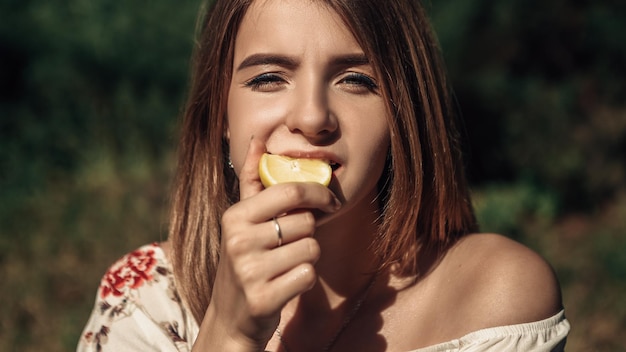 Une femme mange du citron à l'extérieur