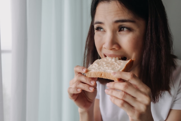 Une femme mange du pain avec du lait concentré sucré comme petit-déjeuner facile