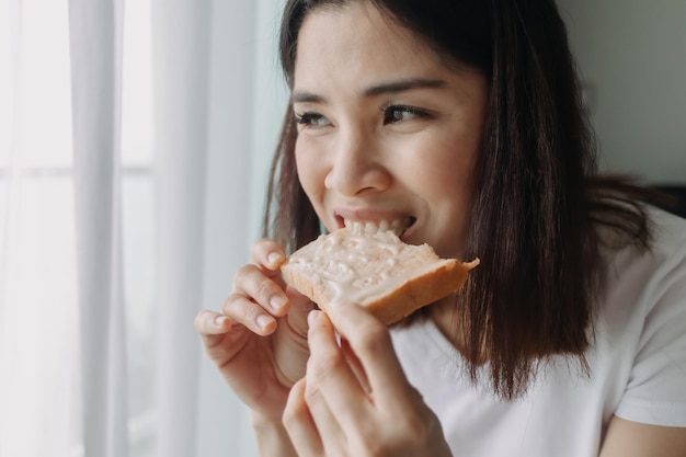 Une femme mange du pain avec du lait concentré sucré comme petit-déjeuner facile