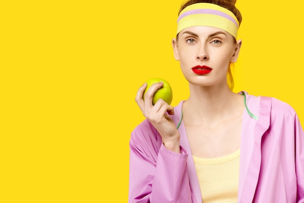 Femme mange une pomme verte sur fond jaune