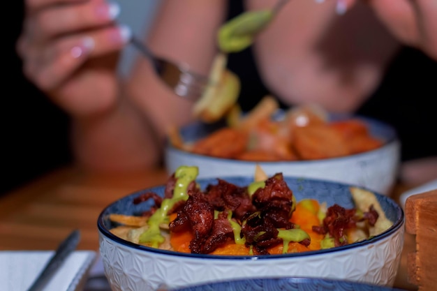 Une femme mange un repas avec une fourchette à la main.