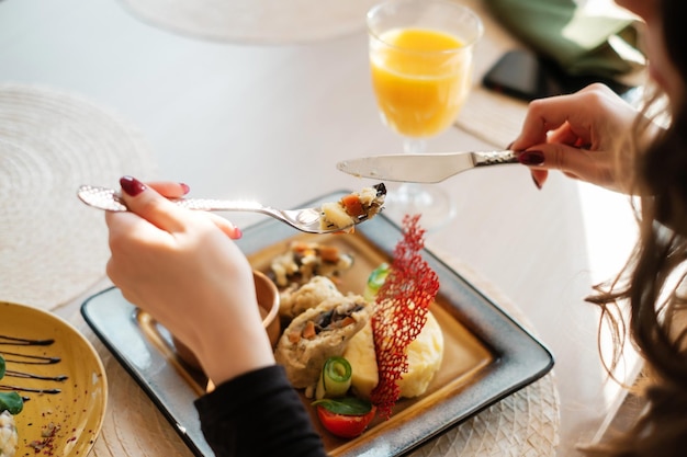 Femme mangeant au restaurant avec fourchette et couteau