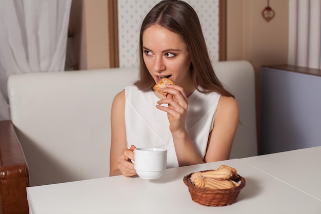 Femme mangeant des biscuits et buvant du thé chaud au café