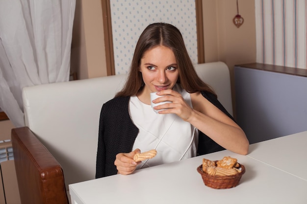 Femme mangeant des biscuits et buvant du thé chaud au café