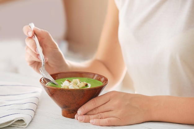 Femme mangeant une délicieuse soupe aux épinards dans la cuisine