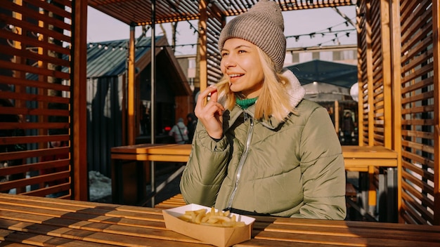 Femme mangeant de délicieuses frites dans un café en plein air Journée d'hiver ensoleillée