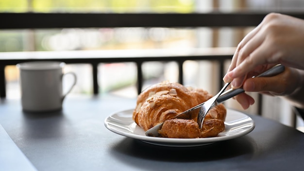 Une femme mangeant un délicieux croissant français frais pour son petit-déjeuner au café