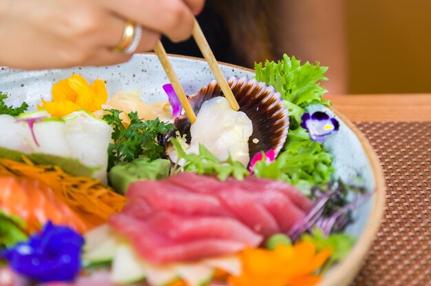 Femme mangeant de délicieux sashimi gros plan sur des baguettes