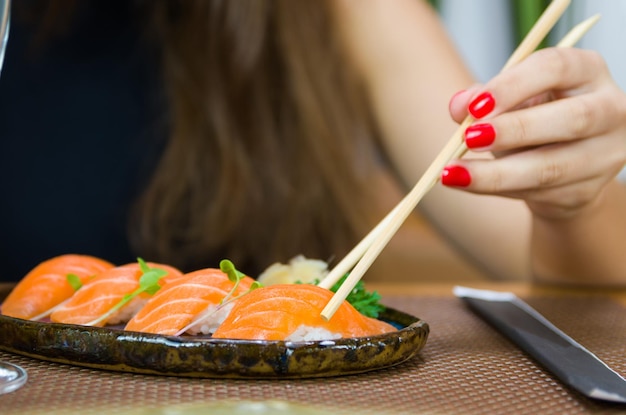 Femme mangeant de délicieux sushis gros plan sur des baguettes