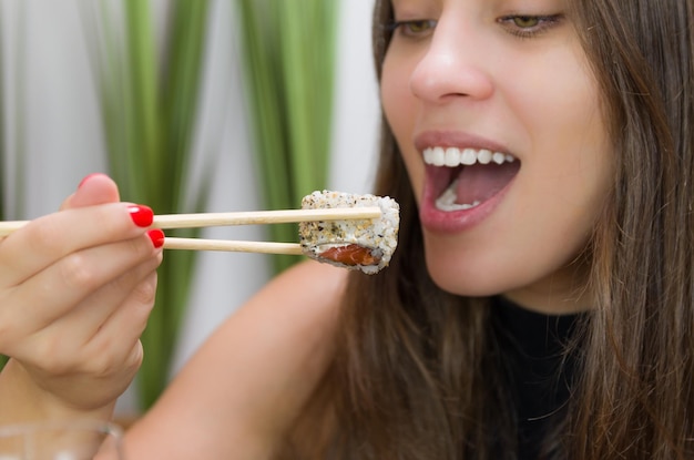 Femme mangeant de délicieux sushis gros plan sur des baguettes