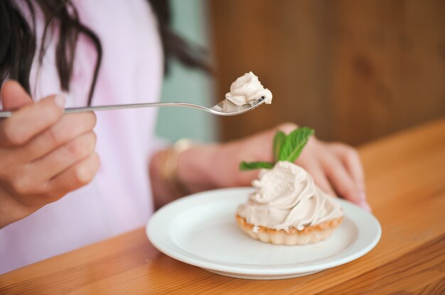 Femme mangeant un gâteau au fromage dans une assiette en céramique