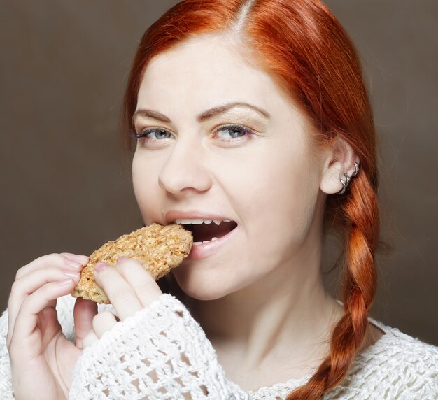 Femme mangeant un gâteau sur fond blanc