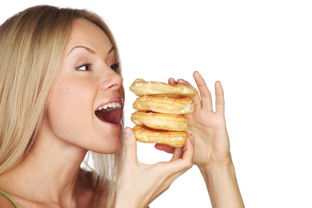 Femme mangeant un gâteau sur un mur blanc