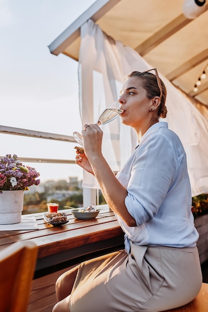 Femme mangeant des huîtres fraîches et buvant du prosecco frais au coucher du soleil d'été