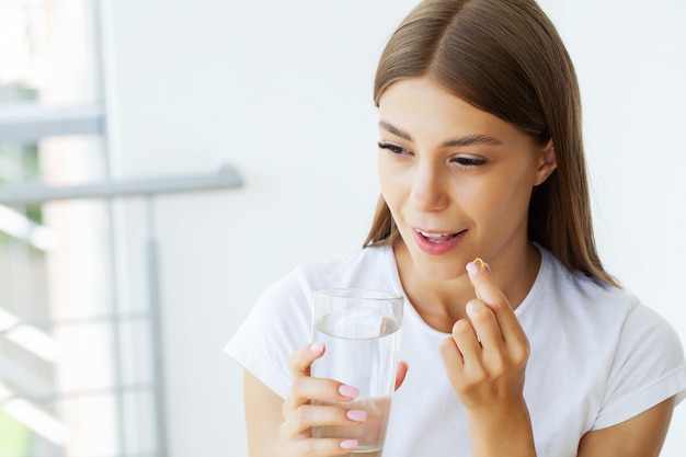 Femme mangeant la pilule et tenant le verre d'eau dans la main