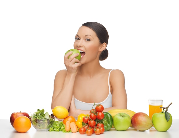 femme mangeant des pommes avec beaucoup de fruits et légumes