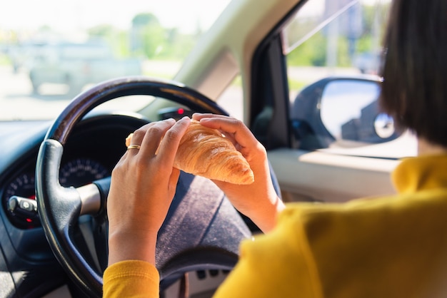 Femme mangeant de la restauration rapide en conduisant la voiture