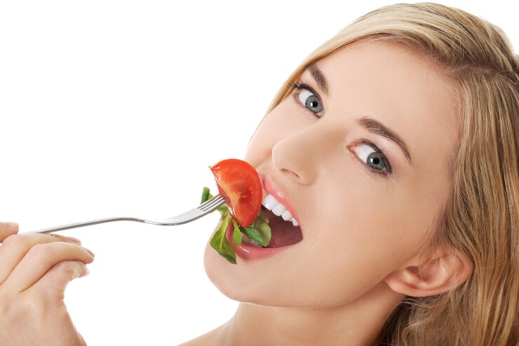 Photo une femme mangeant de la salade sur un fond blanc.