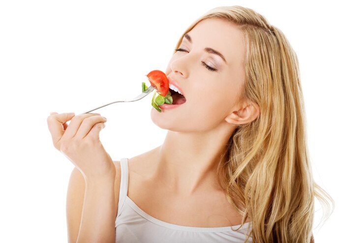 Photo une femme mangeant de la salade sur un fond blanc.