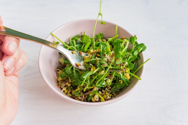 Femme mangeant une salade de petits germes de pois et de haricots germés. aliments sains végétaliens.