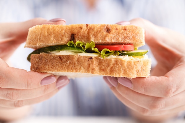 Femme mangeant un sandwich au petit déjeuner et buvant du café tout en travaillant avec un ordinateur portable