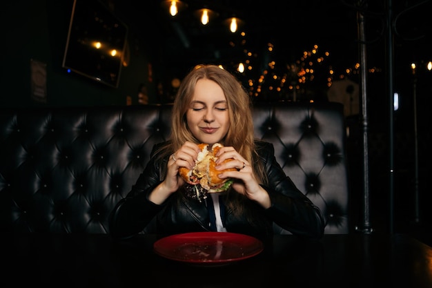 Femme manger un hamburger au café