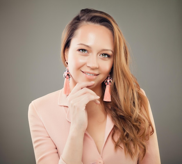 Femme mannequin souriante avec des boucles d'oreilles bijoux roses