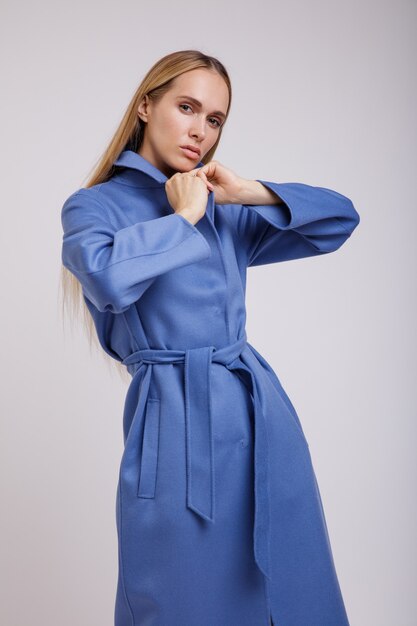 Femme en manteau d'automne bleu posant sur fond blanc Studio Shot silhouette mince