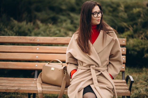 Femme en manteau beige assis sur un banc