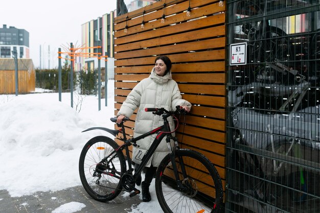 Femme en manteau blanc debout à côté du vélo