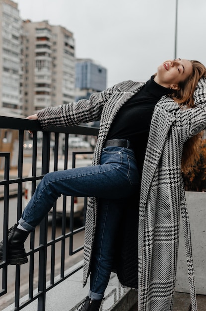 Une femme en manteau et jeans s'appuie sur une balustrade