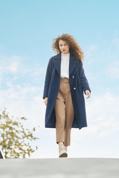 Femme en manteau de laine marche sur le pont en journée ensoleillée