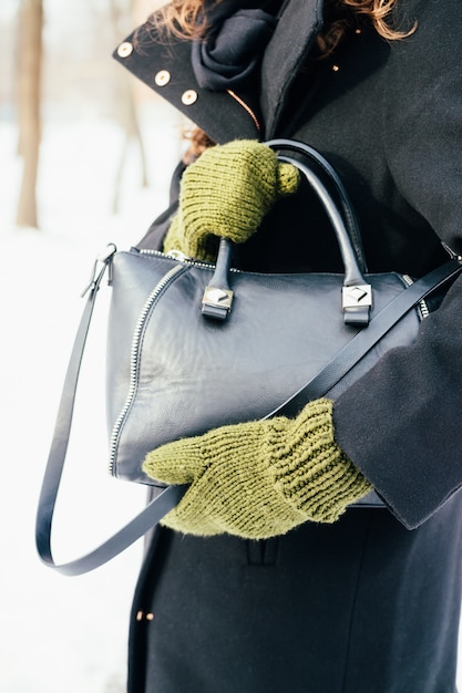 Femme, manteau noir, vert, gants, tient, a, sac à main, gros plan