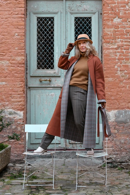 Une femme avec un manteau en terre cuite et des gants en cuir