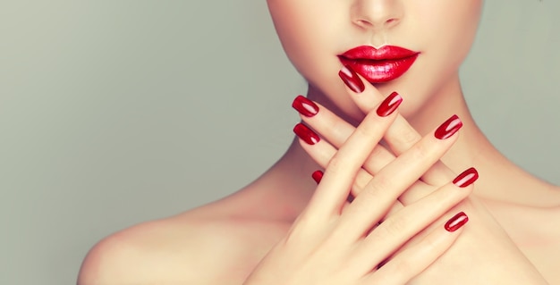 Photo femme avec manucure rouge vif sur les ongles et lèvres rouges bien en forme