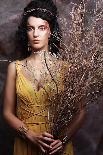 Femme avec un maquillage lumineux avec des branches sèches