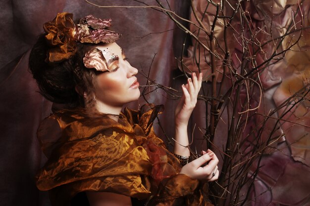 Femme avec un maquillage lumineux avec des branches sèches