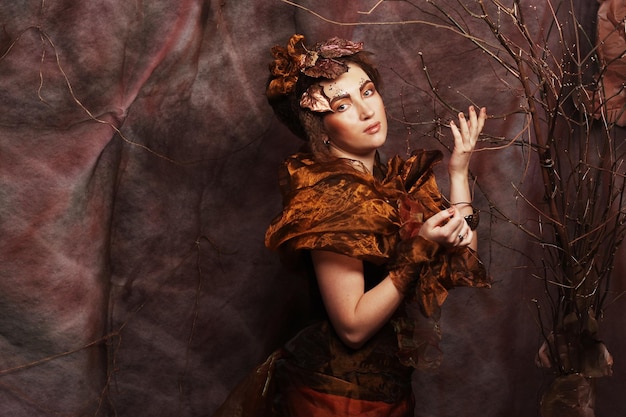 Femme avec un maquillage lumineux avec des branches sèches