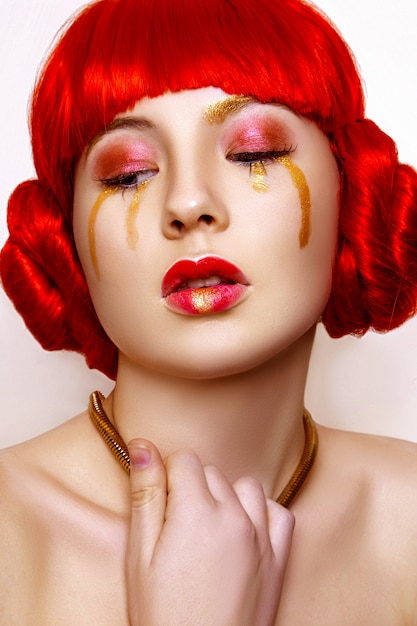 Femme avec maquillage rouge et or et cheveux roux