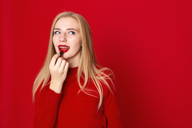 Femme maquillant - appliquer du rouge à lèvres sur les lèvres en studio