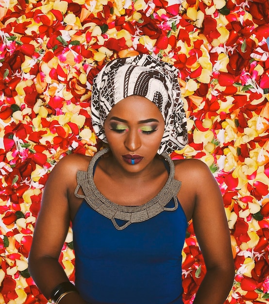 Femme maquillée et vêtue d'un foulard alors qu'elle est allongée sur des pétales